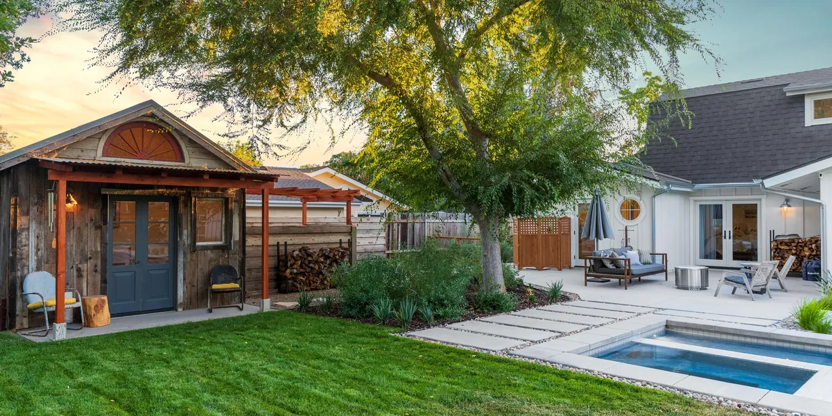 Backyard Design | AAA Landscaping Beautifully landscaped backyard featuring a lush green lawn, rustic wooden shed, modern patio seating area, and a small pool, creating a cozy outdoor retreat serviced by AAA Landscaping.