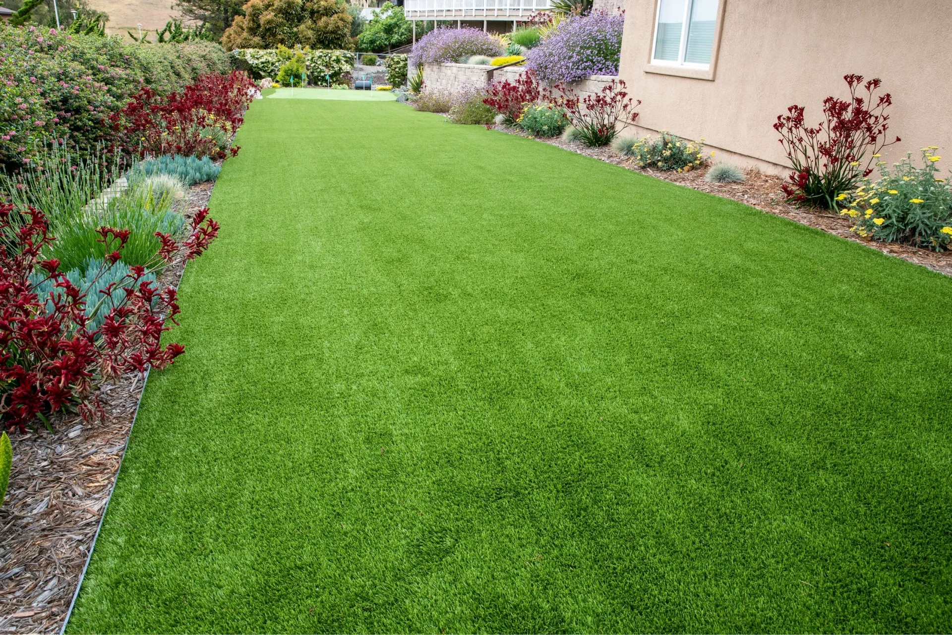 Synthetic Turf | Backyard Lush green synthetic turf in a beautifully landscaped backyard, offering a low-maintenance, eco-friendly lawn solution for a perfect outdoor space.